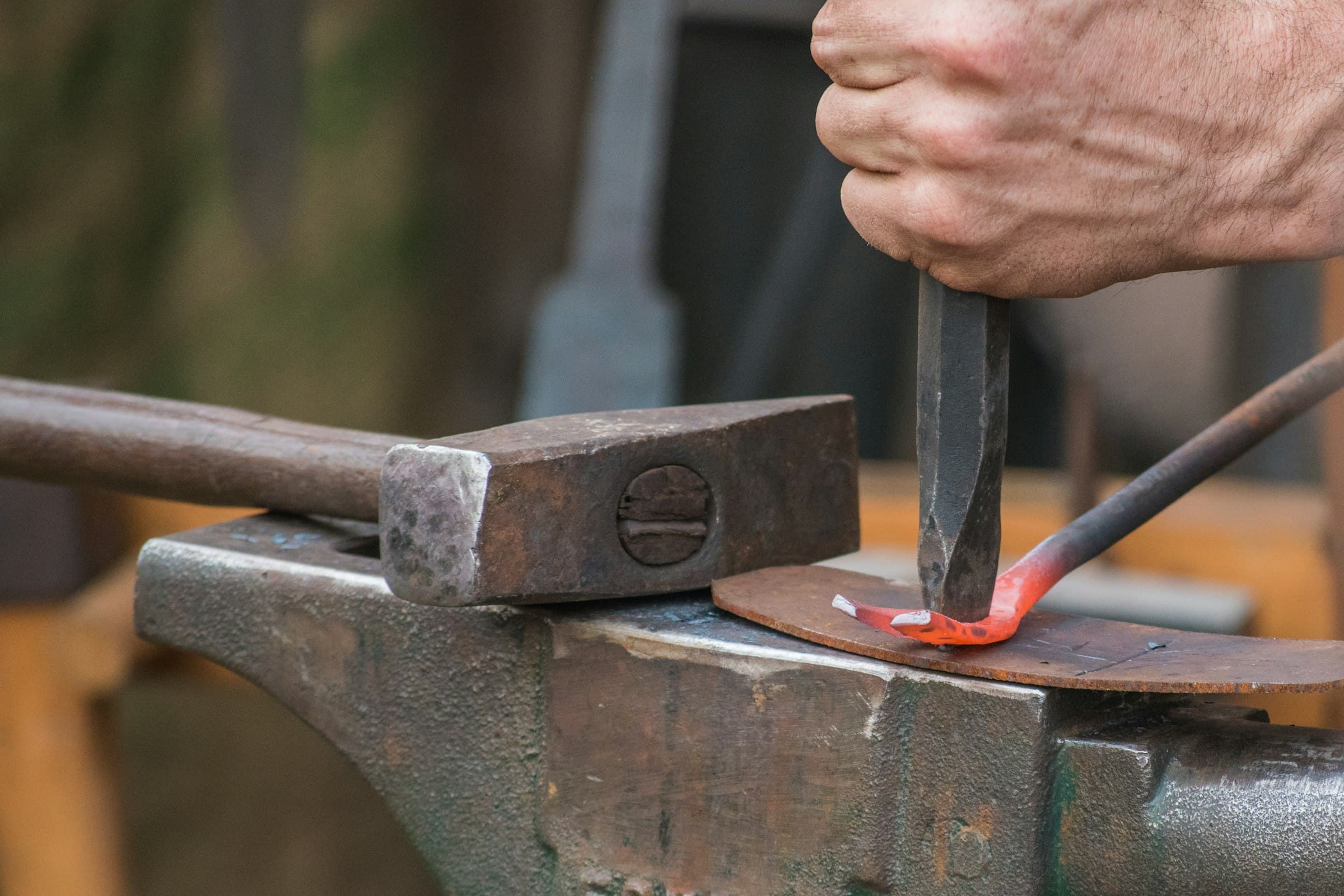 Worker holding burning metal rod in a forge