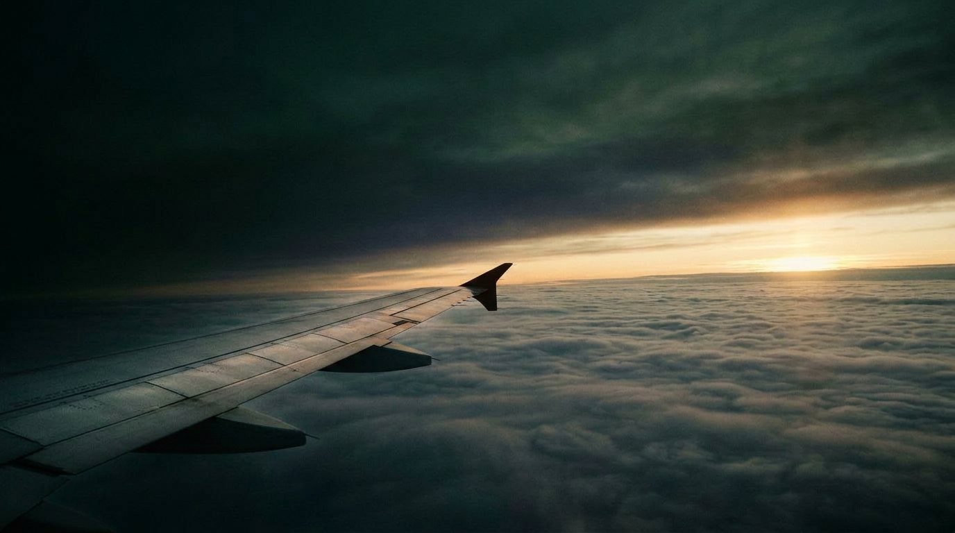 An aircraft wing over clouds at sunset