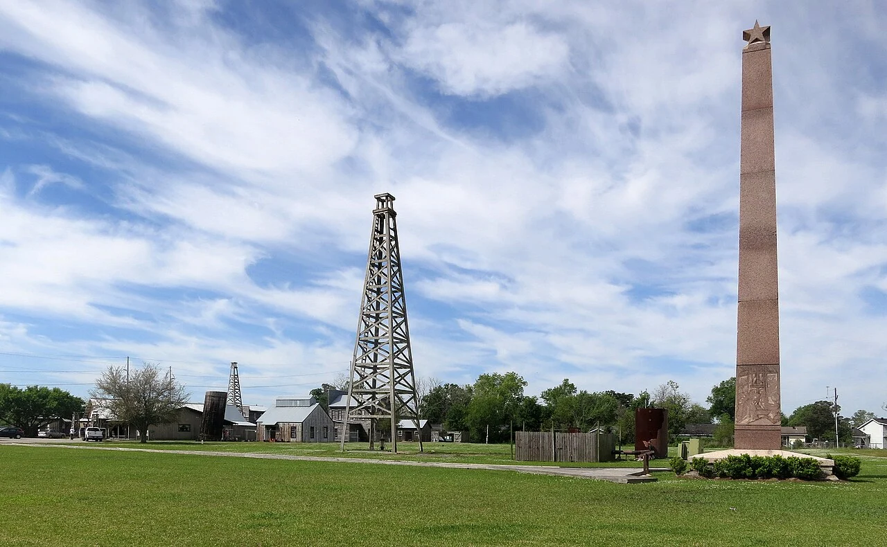 An oil derrick and tall brick monument at the Spindletop–Gladys City museum in Beaumont
