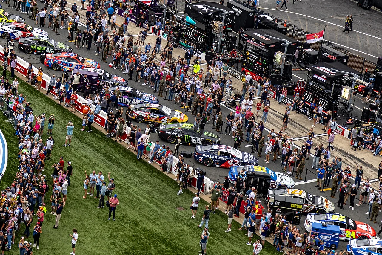 NASCAR race cars and team crews lined up at Charlotte Motor Speedway for the 2025 Coca-Cola 600